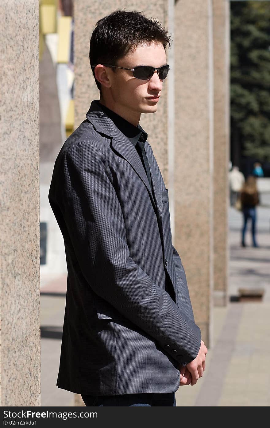 Man in sunglasses stands near office building