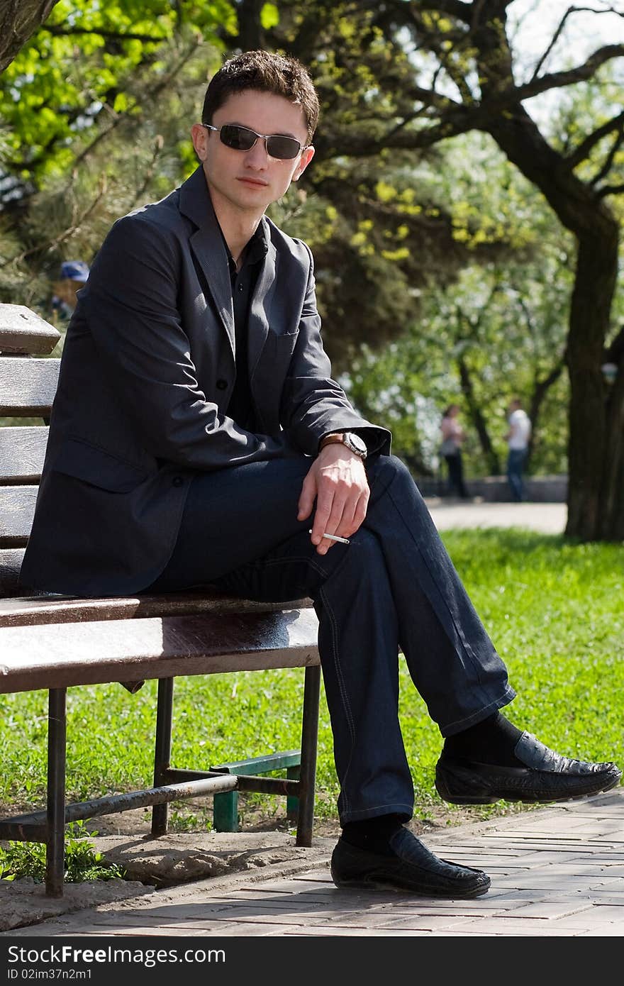 Guy with a cigarette on a bench in the park