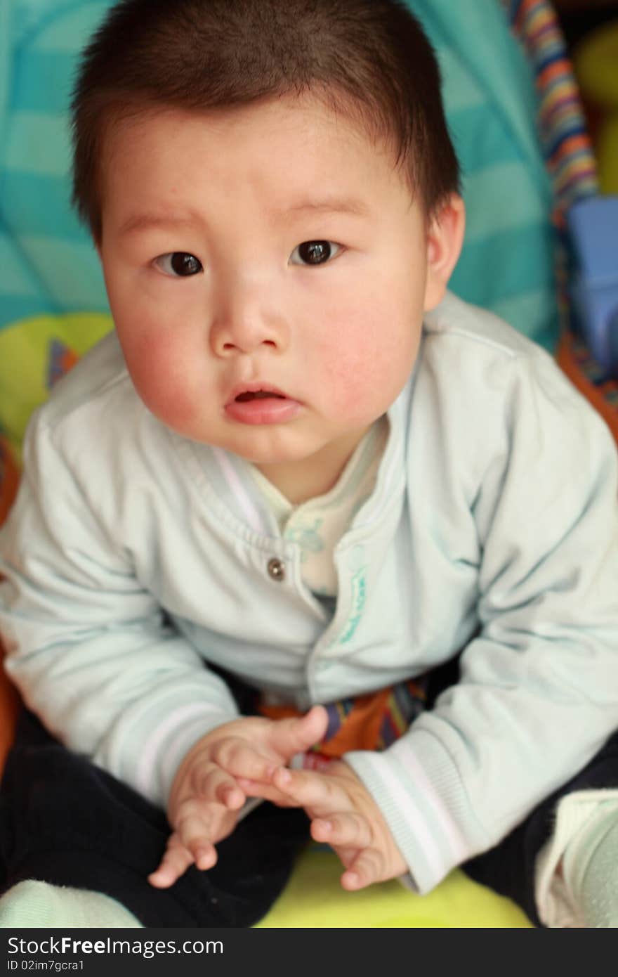 Lovely Chinese baby is sitting on a chair