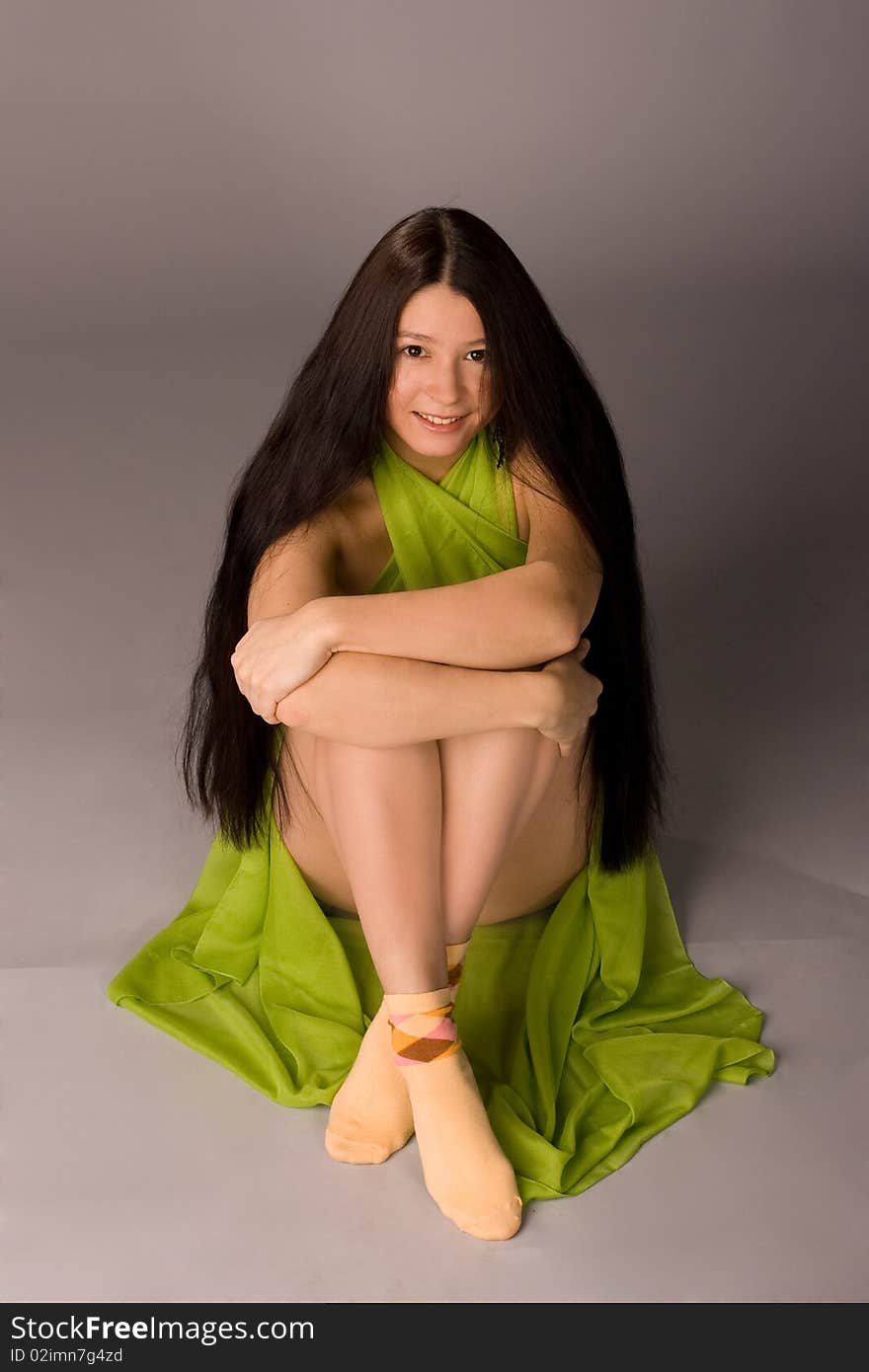 Attractive girl sitting on the floor - gray background