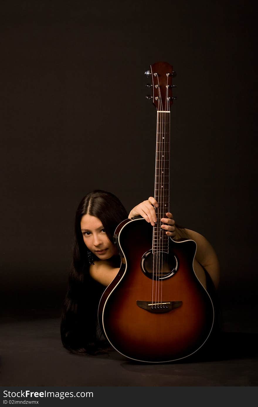 Attractive girl hiding behind a guitar