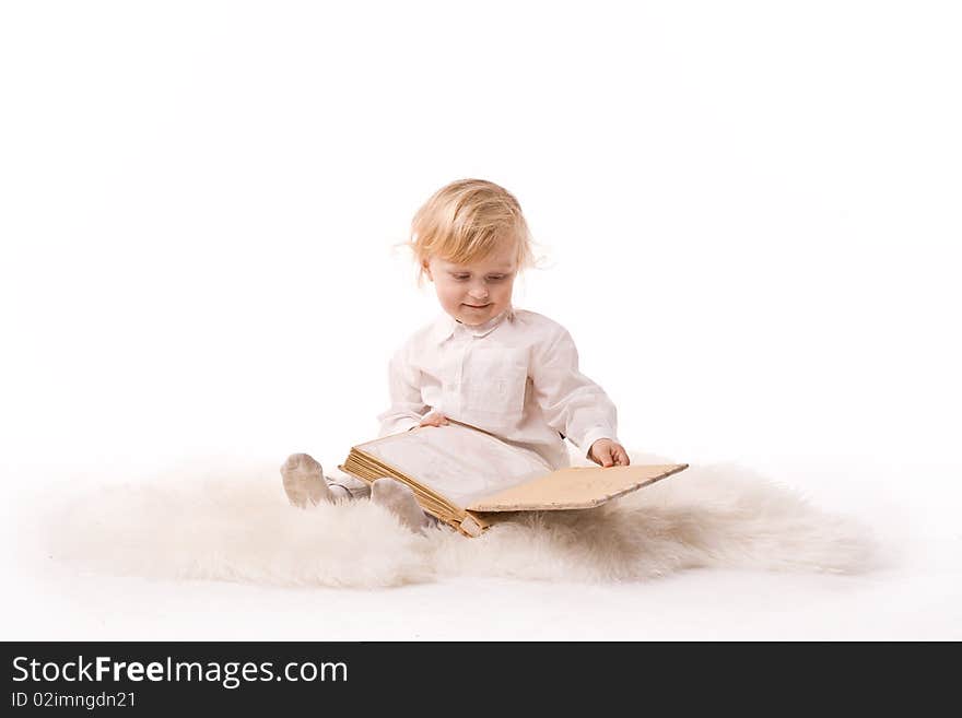 Dear baby sitting and watching a book on a white background. Dear baby sitting and watching a book on a white background