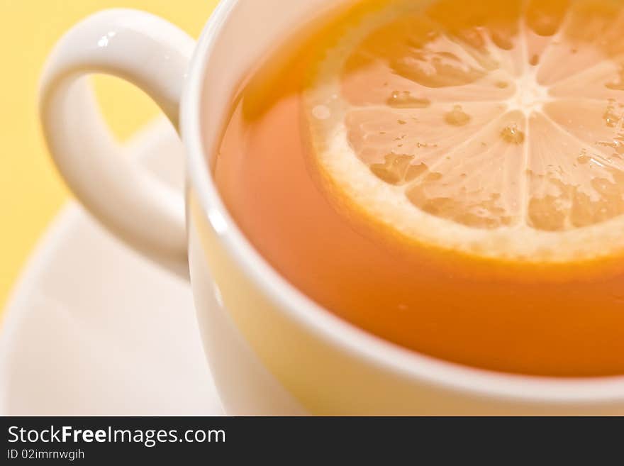 Cup of tea with lemon over yellow. Cup of tea with lemon over yellow