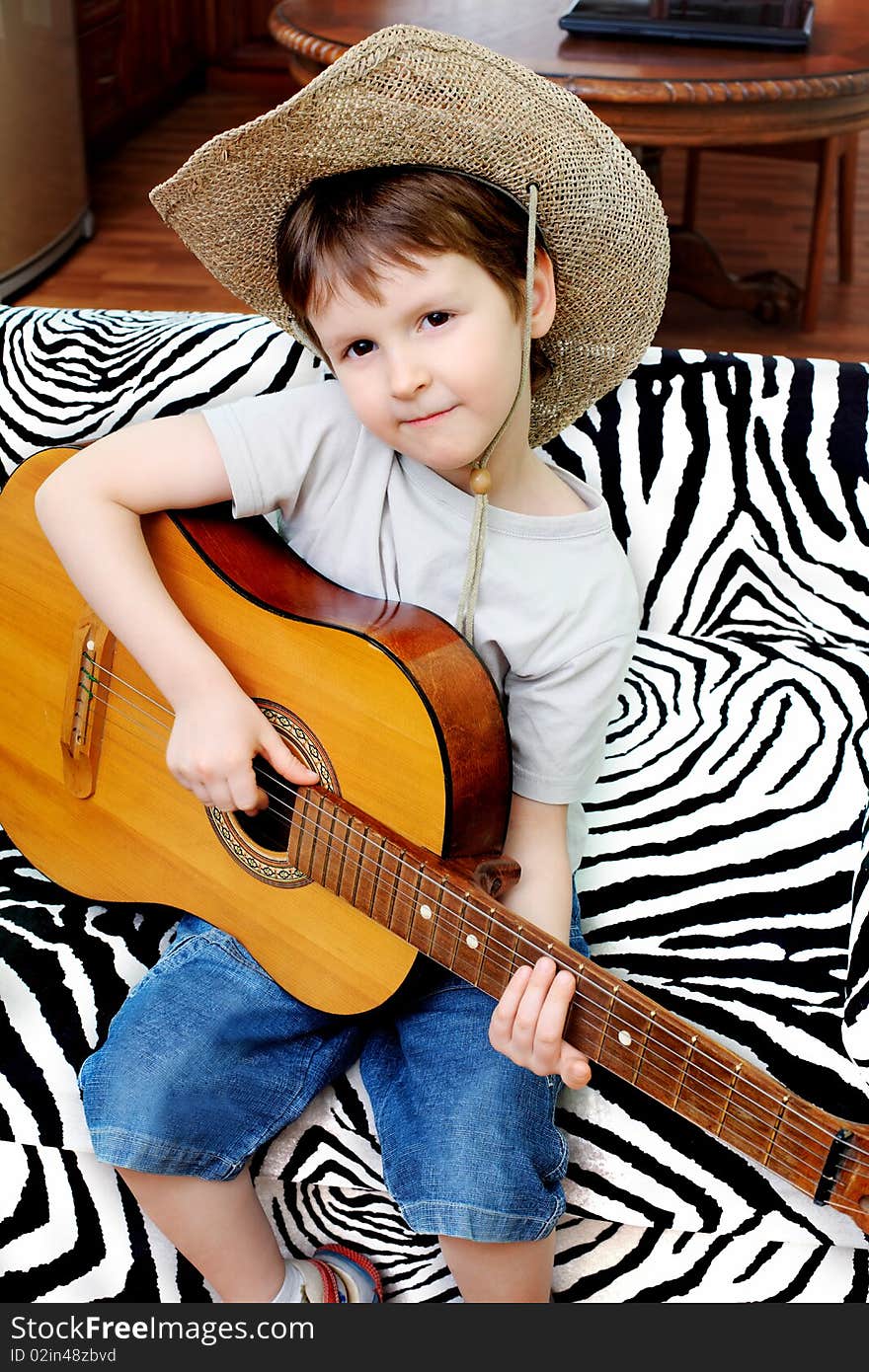 Shot of a little boy playing his guitar at home. Shot of a little boy playing his guitar at home.