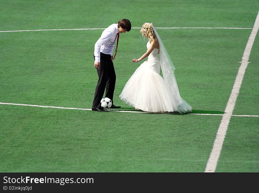 Young wedding couple playing football on the green field. Young wedding couple playing football on the green field