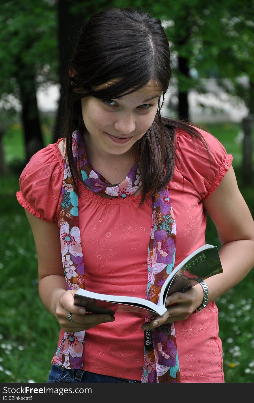 Beautiful young girl reading a book in the natural