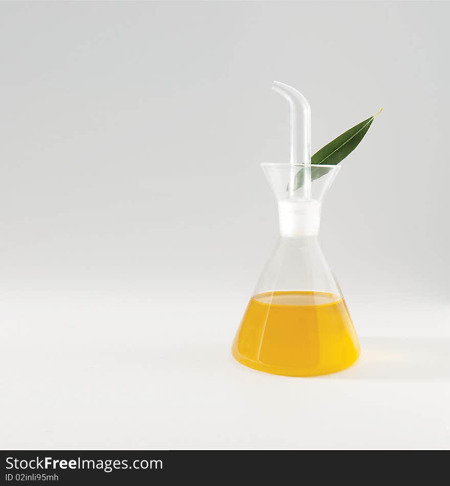 Olive oil in a glass can white an olive leaf