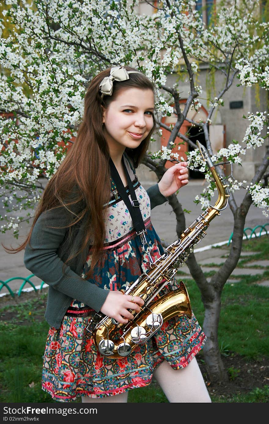 Beautiful smiling girl with saxophone, spring tree. Beautiful smiling girl with saxophone, spring tree