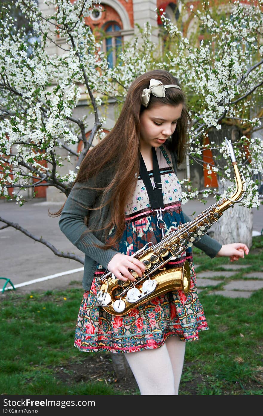 Beautiful smiling girl with saxophone, spring tree. Beautiful smiling girl with saxophone, spring tree