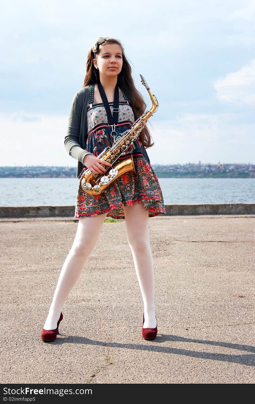 Beautiful girl with saxophone, spring beach