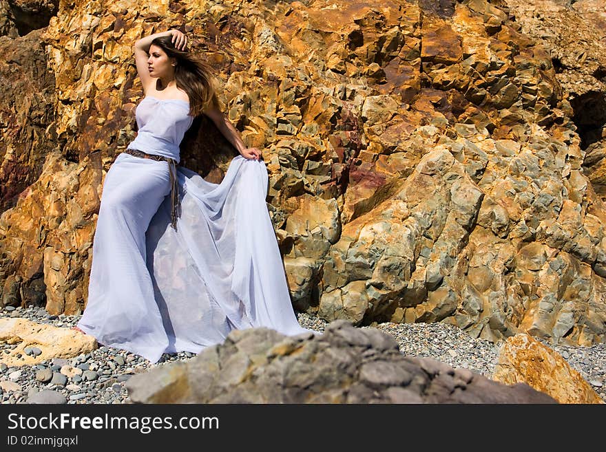 Woman in white dress from material and rocks