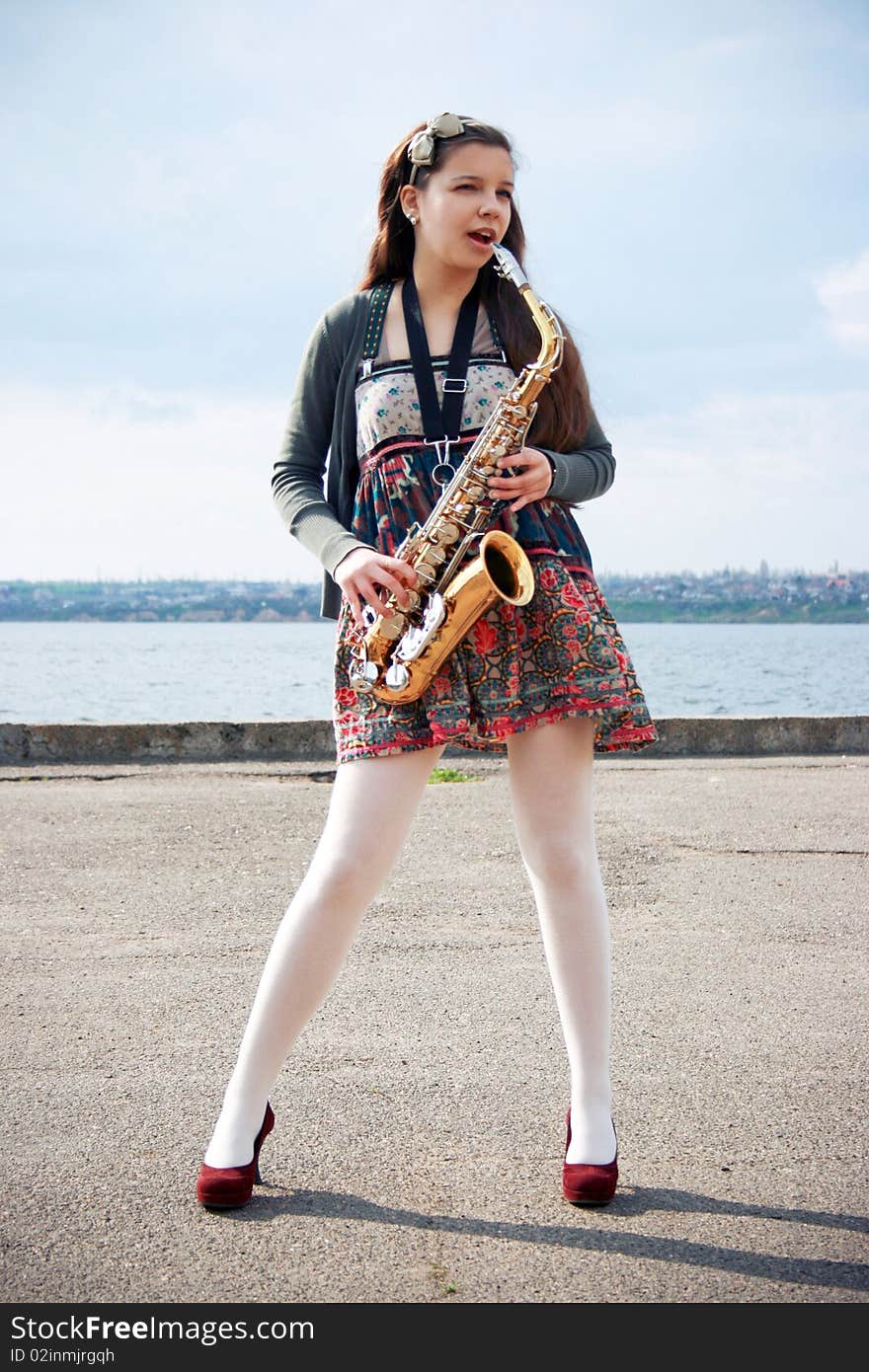 Beautiful girl with saxophone, spring beach