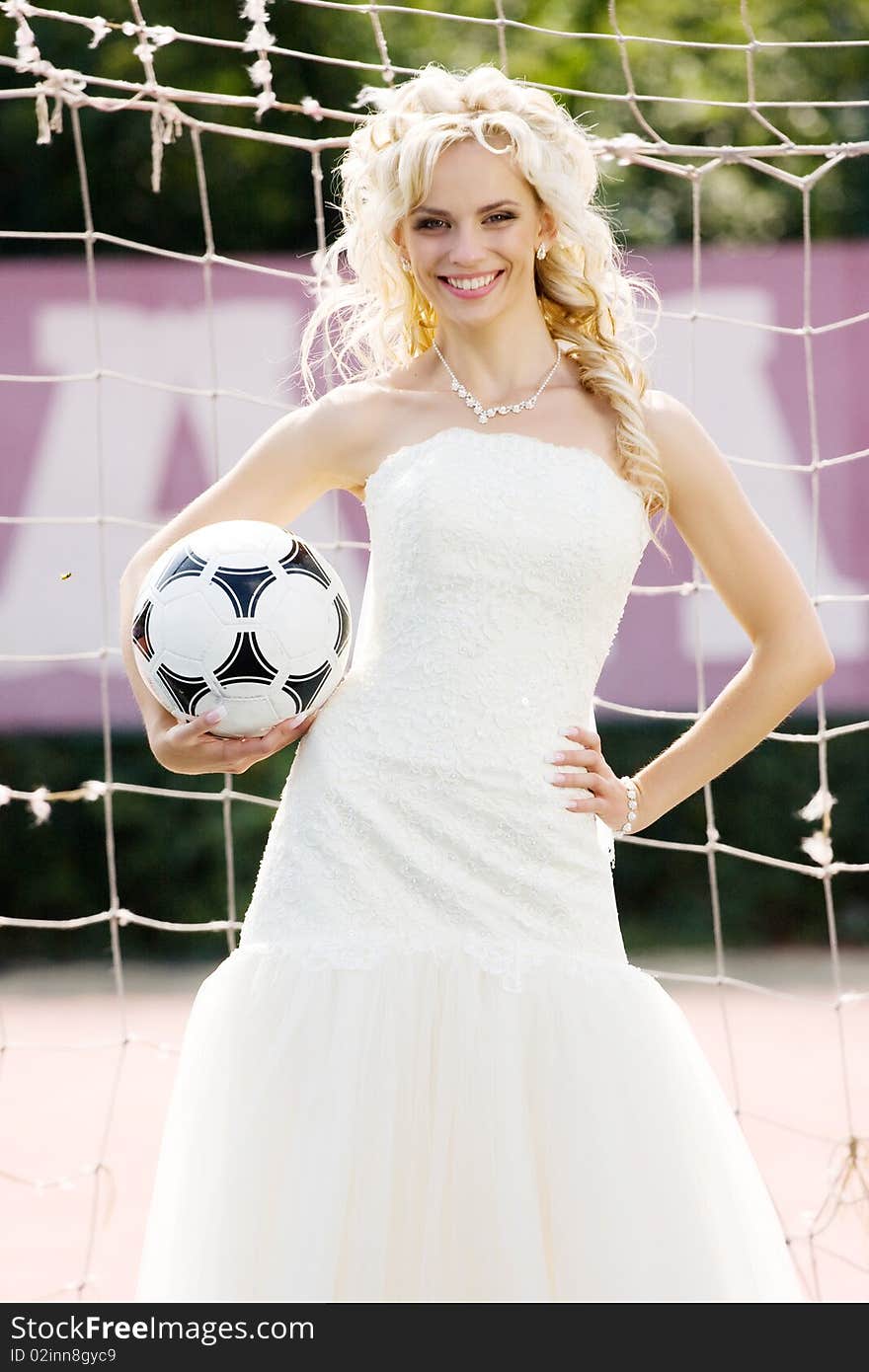 Young beautiful bride standing on the gate with ball. Young beautiful bride standing on the gate with ball