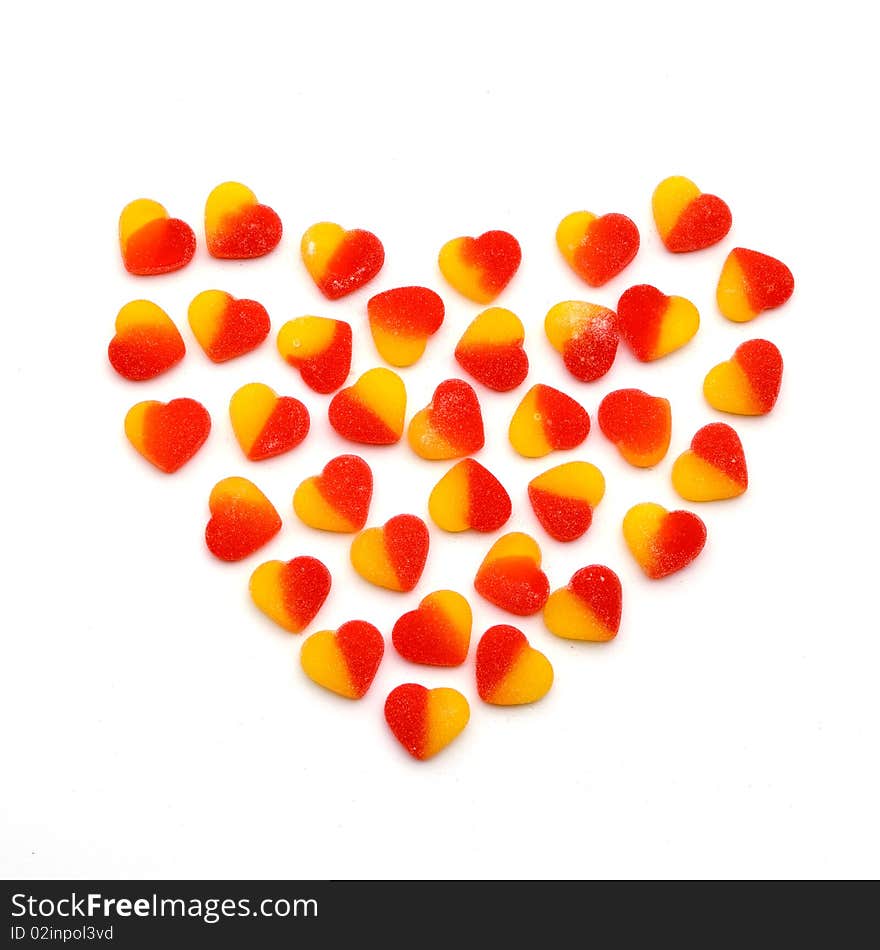 Large heart made from the small red and yellow fruit candies hearts on a white background. Symbol of sweet love. Large heart made from the small red and yellow fruit candies hearts on a white background. Symbol of sweet love.