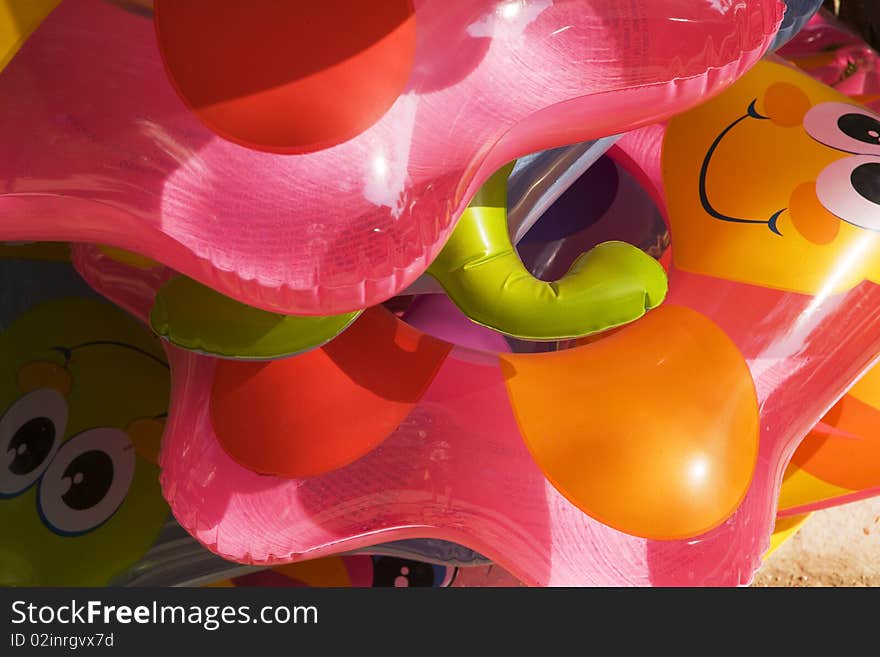 A stack of colorful children's float toys is stacked and waiting for a day of fun at the beach. A stack of colorful children's float toys is stacked and waiting for a day of fun at the beach.