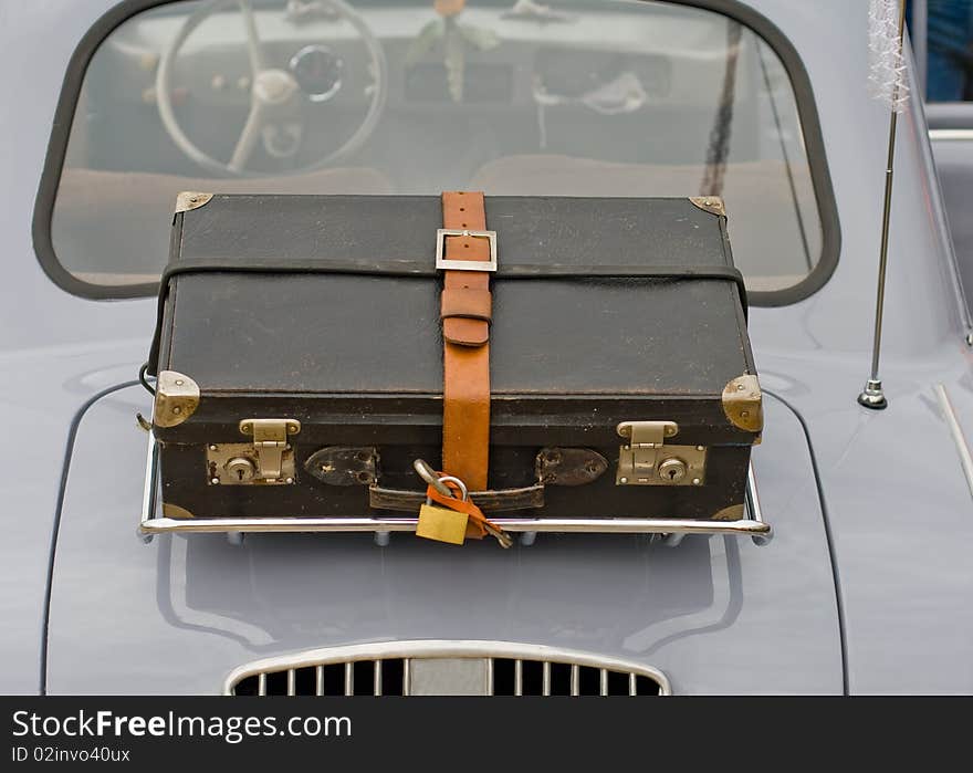 An old suitcase on the back of an old car. An old suitcase on the back of an old car