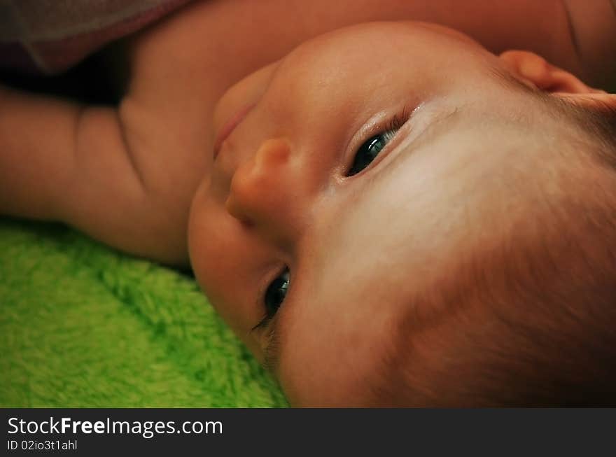 Two months old baby girl wrapped in a green blanket