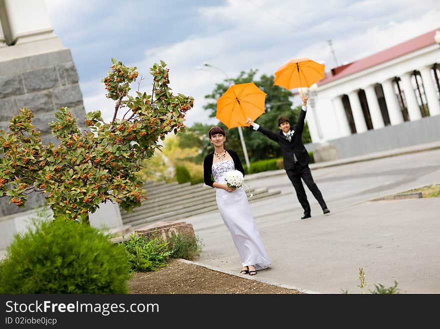 Bride and groom with orange umbrellas