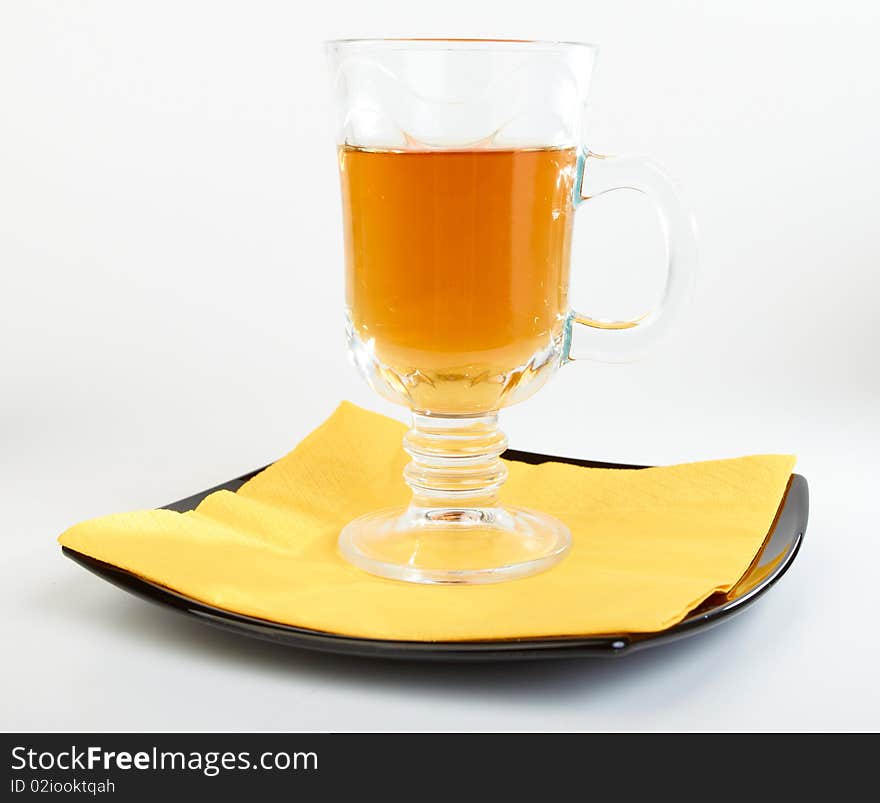 Сup of tea on black plate with yellow serviette on white background