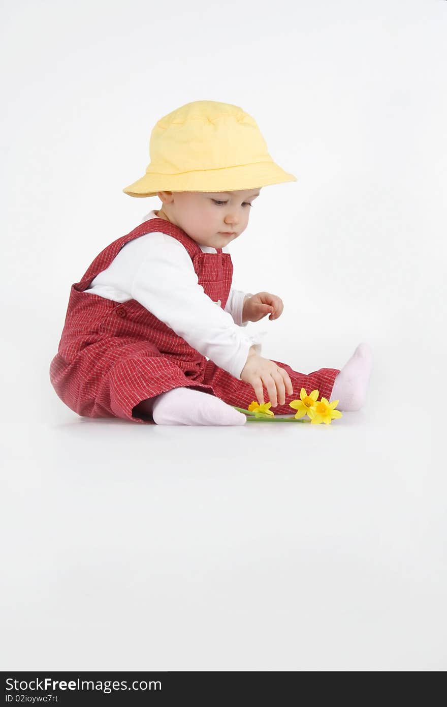 Sitting little girl in hat and with flower on white background.