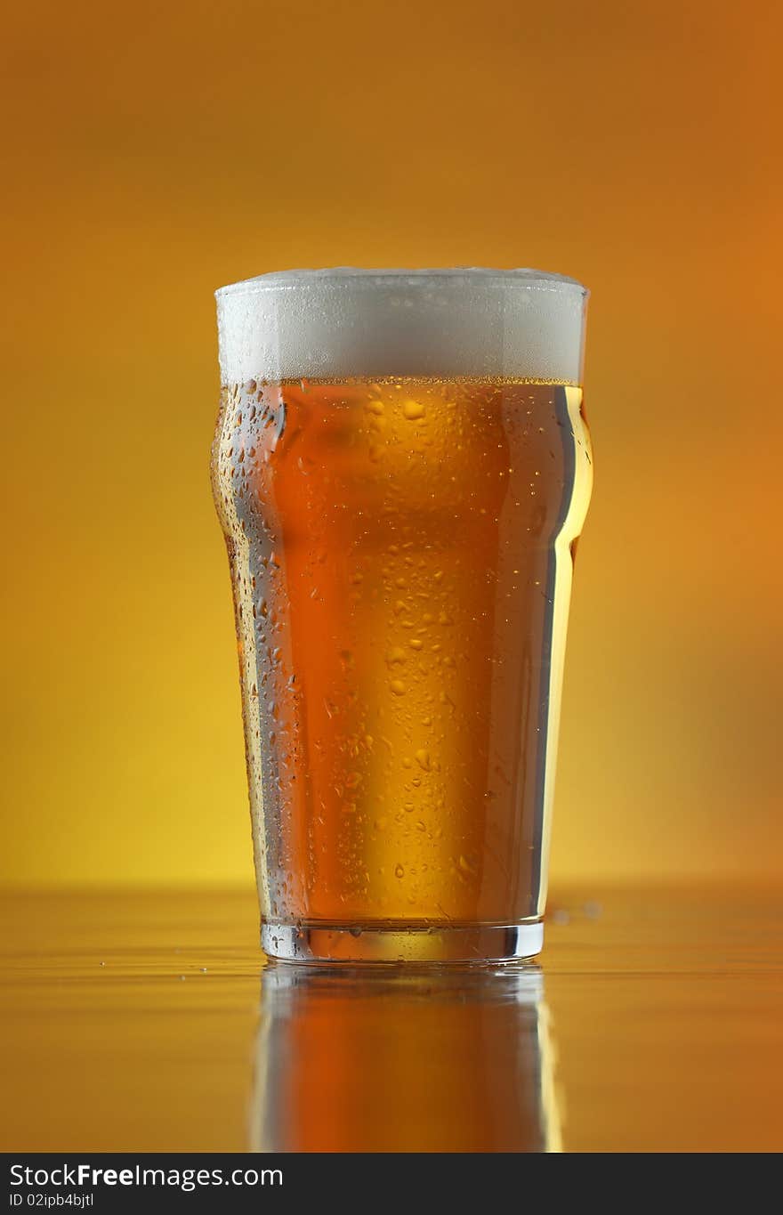 Fresh refreshing beer on a golden background