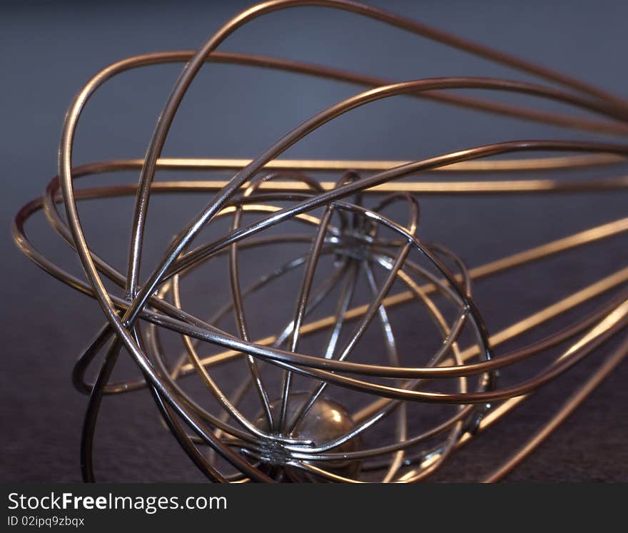 A modern whisk with a dark background. A modern whisk with a dark background