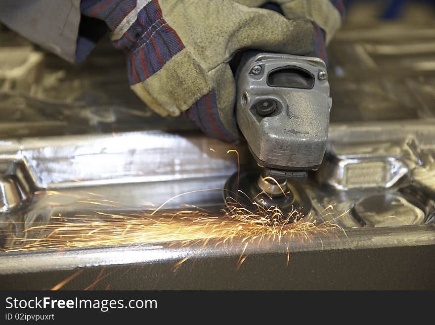 Man using a angle grinder on metal surface with sparks