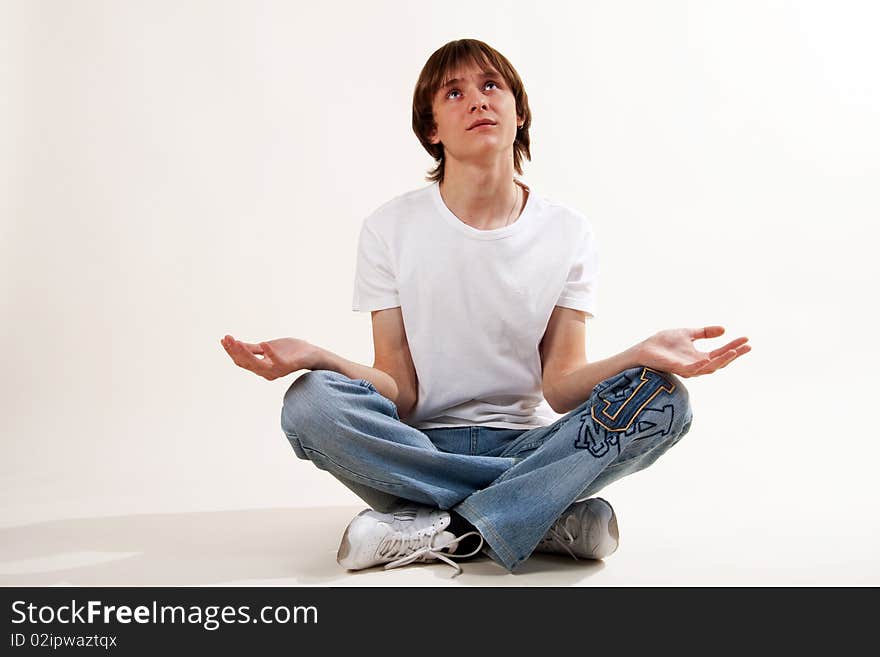 Young man sitting on the floor. In expectation of something. With the hands placed on the different parties looks at top.