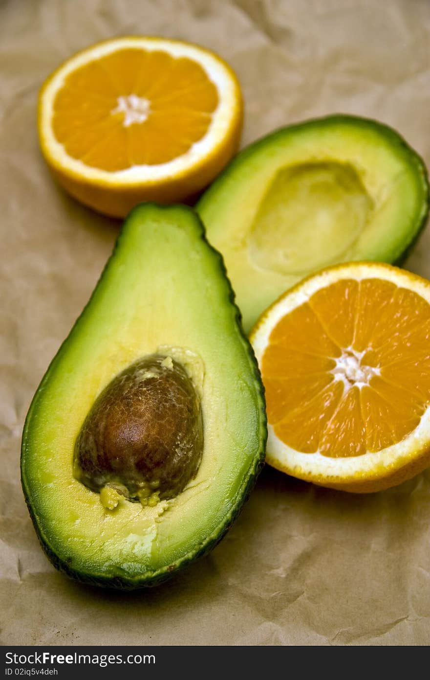 Avocados and oranges against a worn paper background.