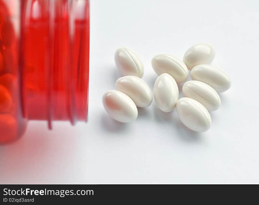 Close up of red vitamin bottle with white capsules. Close up of red vitamin bottle with white capsules