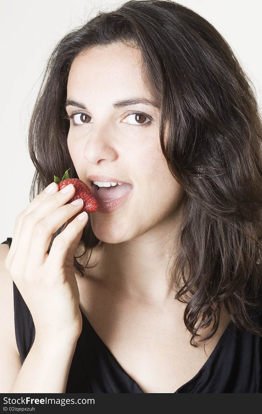 Young woman eating red strawberry