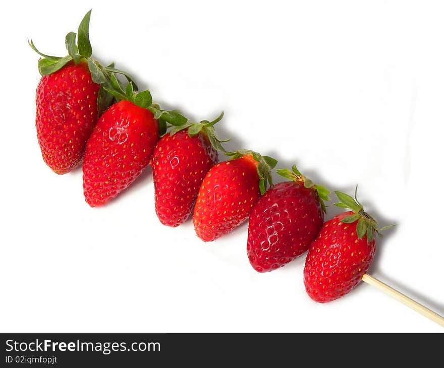 juicy ripe strawberries on a wooden stick isolated on a white background