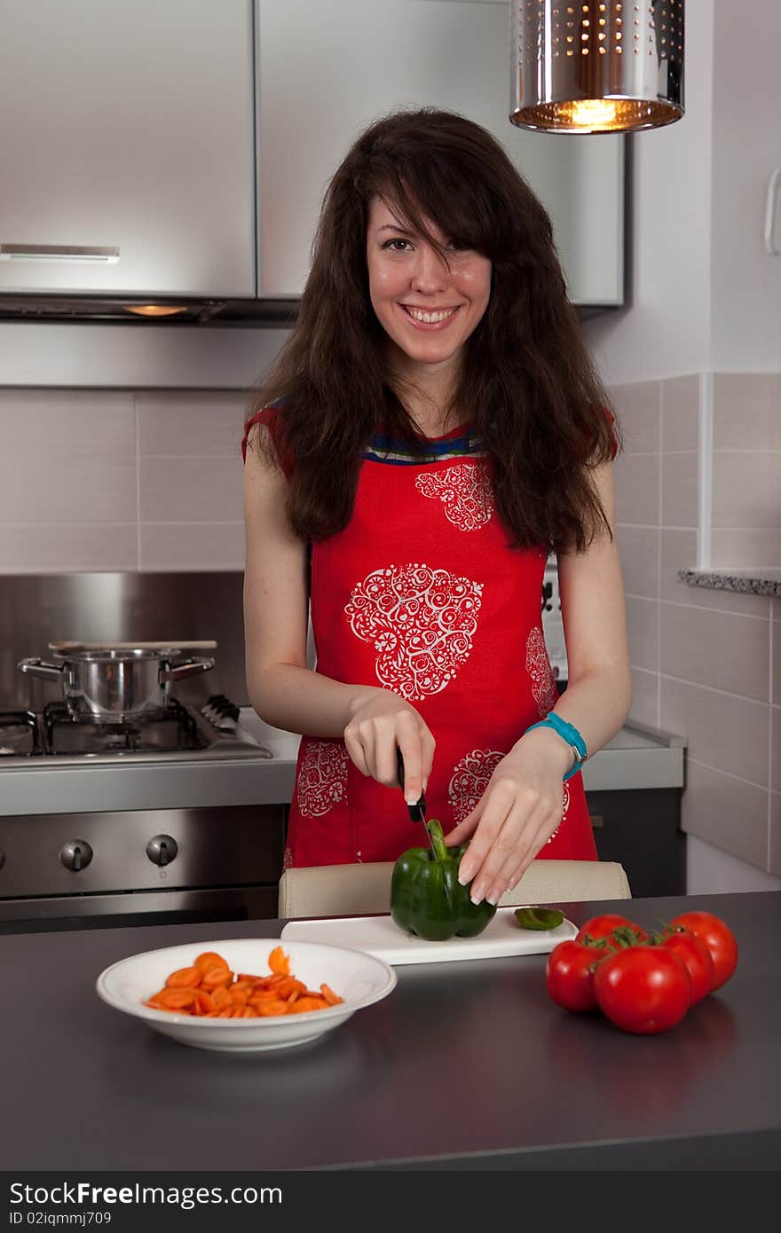 Pretty girl cooking and cutting green pepper in the kitchen. Pretty girl cooking and cutting green pepper in the kitchen.