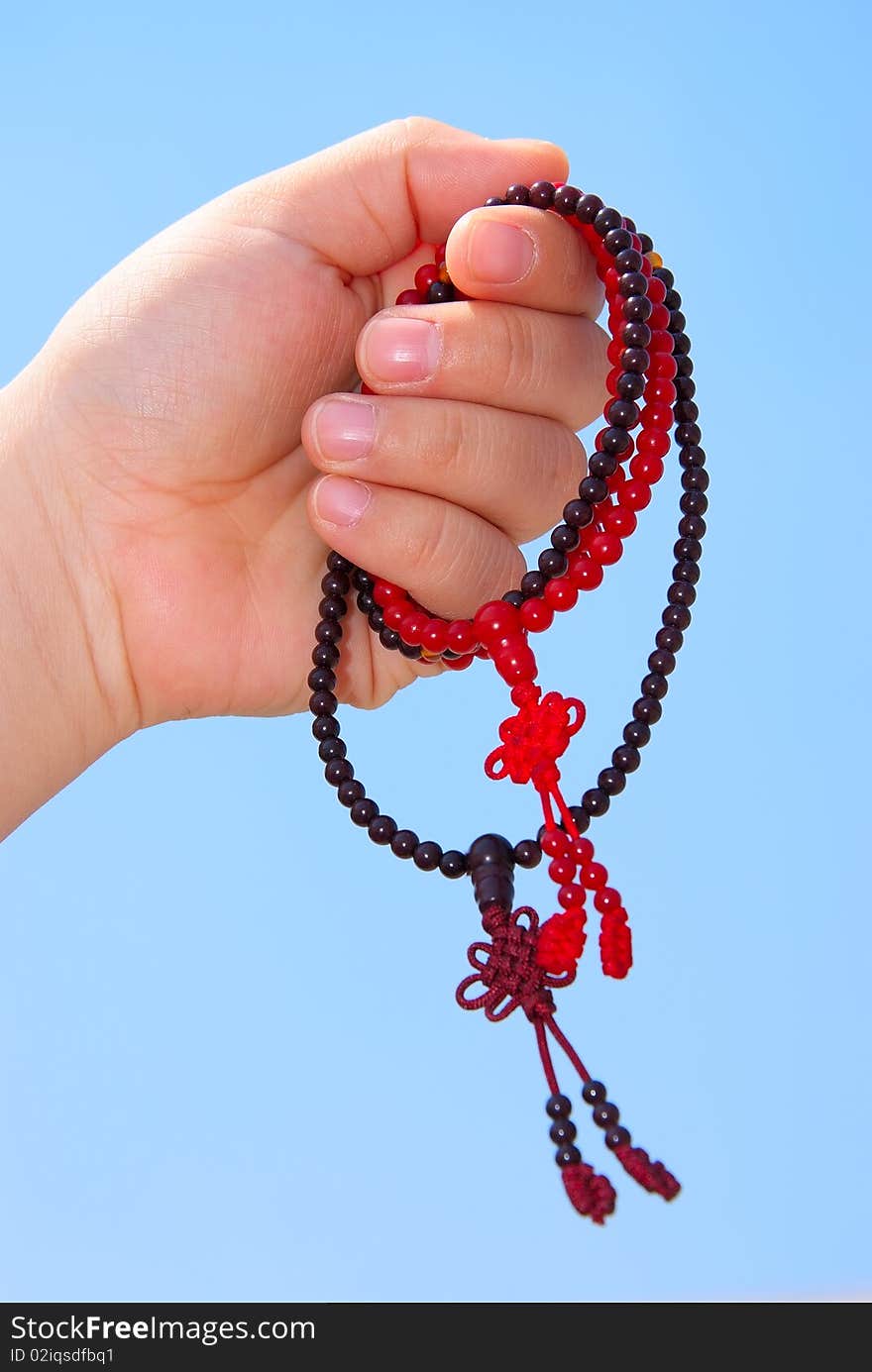 Prayer beads in her hands.Against the background of blue sky.