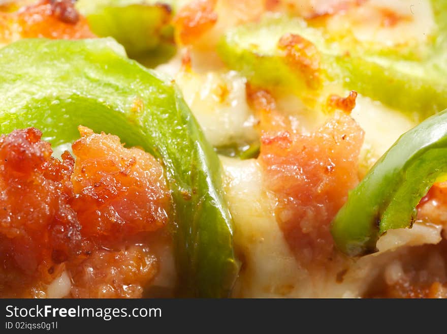 An extreme close up of pizza toppings on a slice, including meat, cheese and green peppers. An extreme close up of pizza toppings on a slice, including meat, cheese and green peppers