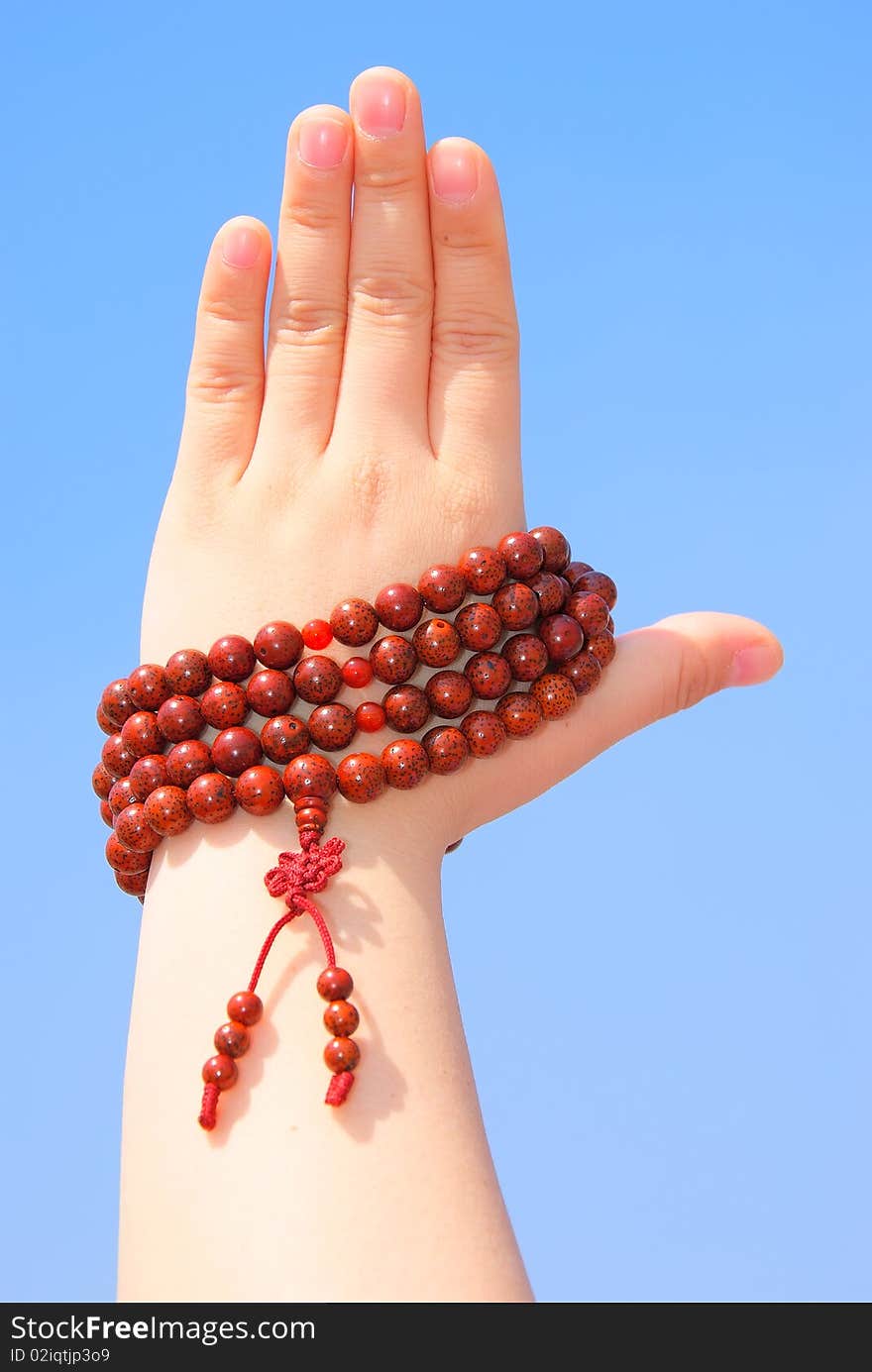 Prayer beads in her hands.Against the background of blue sky.