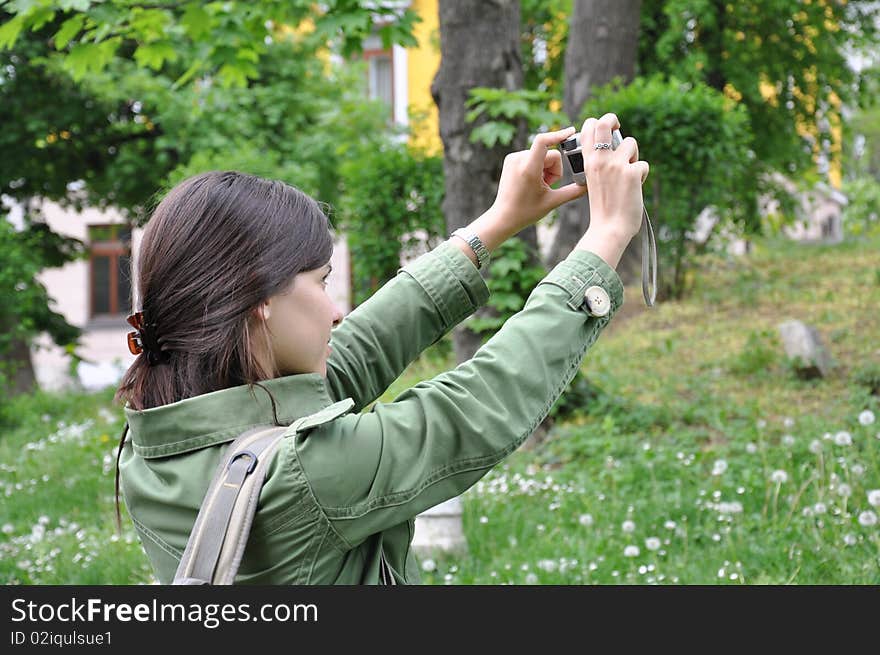 Young beautiful girl taking a photo in nature