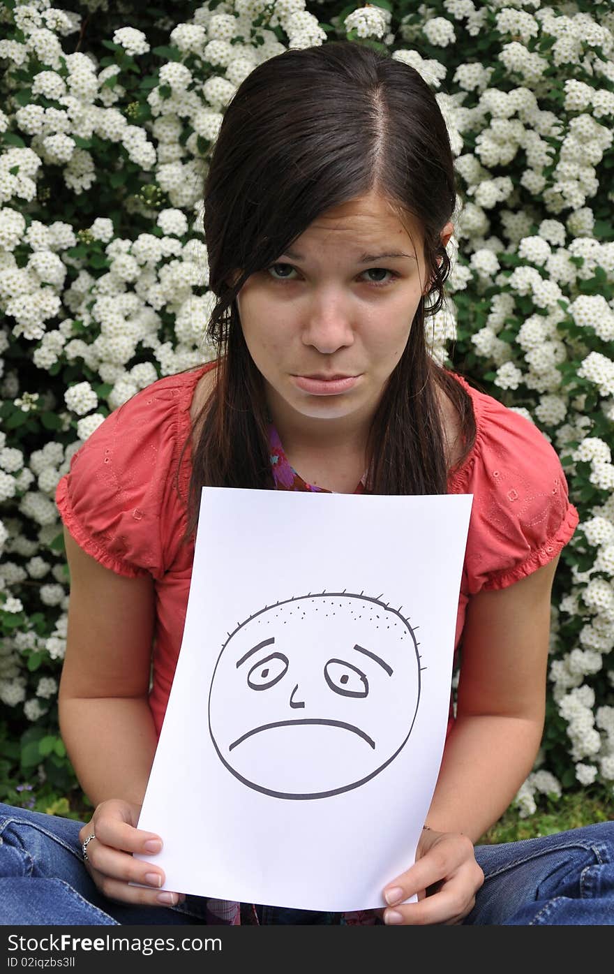 Beautiful girl holding a paper with a drawn face e