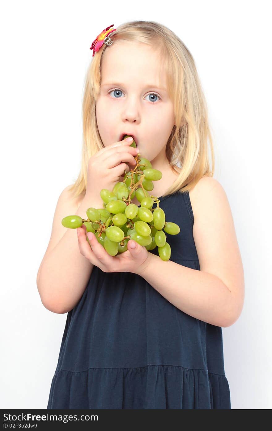 Beautiful girl in blue dress eats green grapes. Series - family with fruits and vegetables. Beautiful girl in blue dress eats green grapes. Series - family with fruits and vegetables