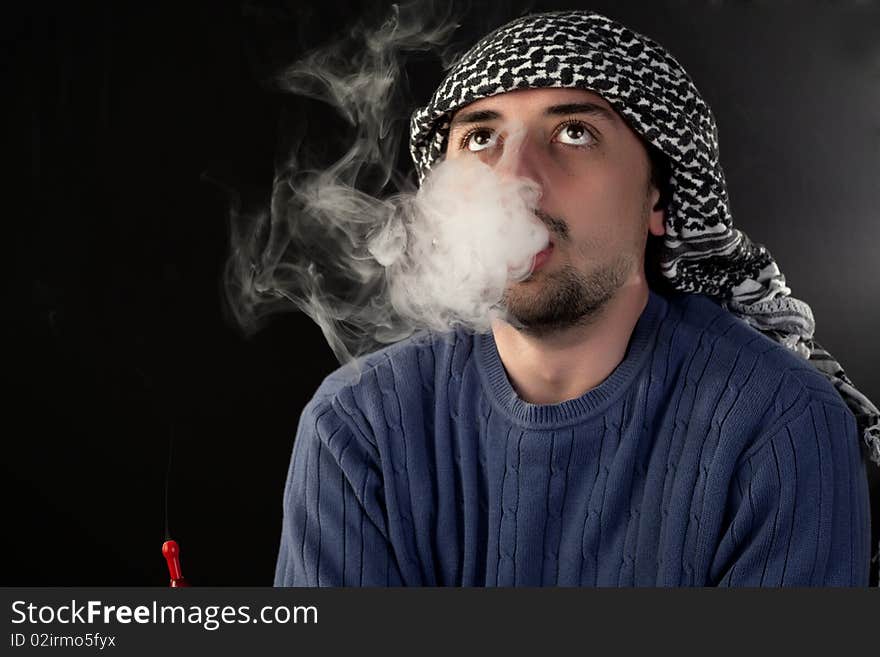 Young man enjoying hookah on a black background. Young man enjoying hookah on a black background