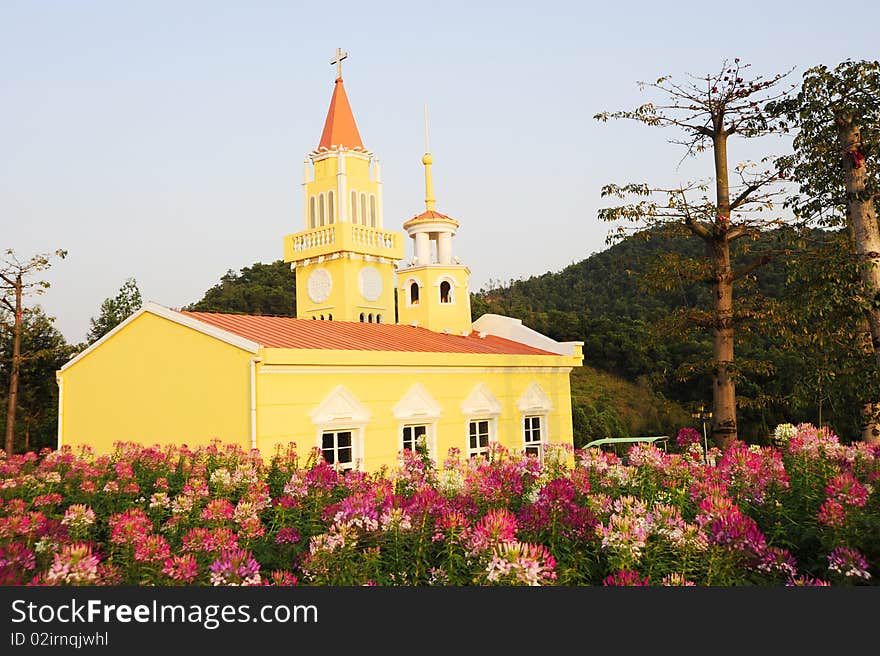 A yellow church.In the garden.Colorful.with tree and flower.