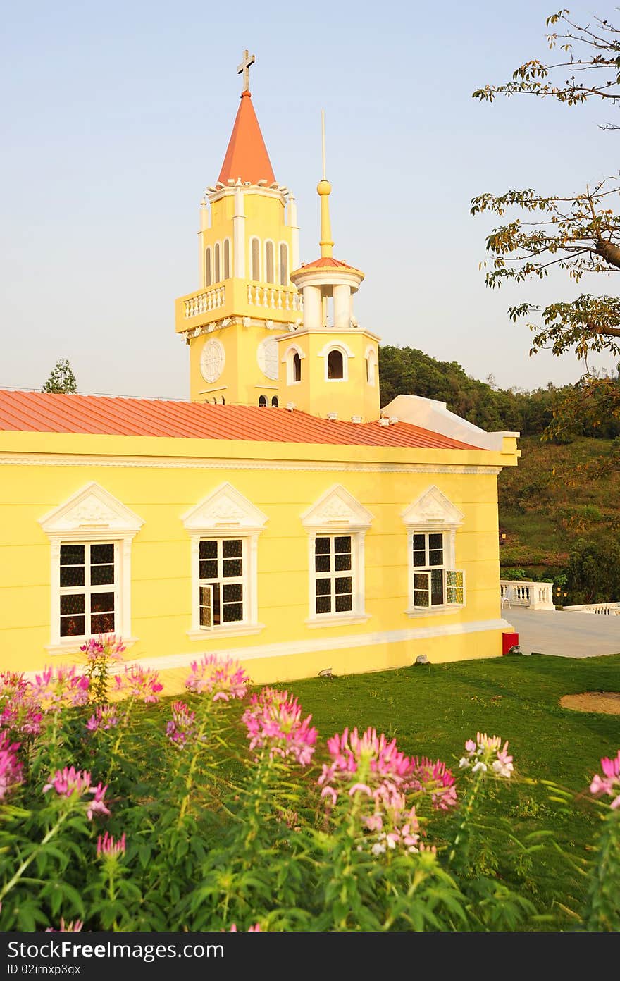 A yellow church.In the garden.Colorful.with tree and flower.