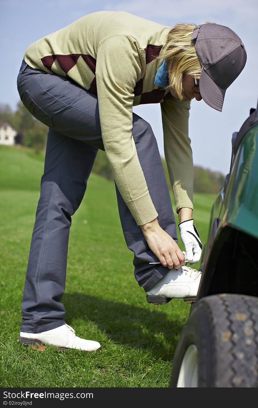 Woman tying shoes at the golf course