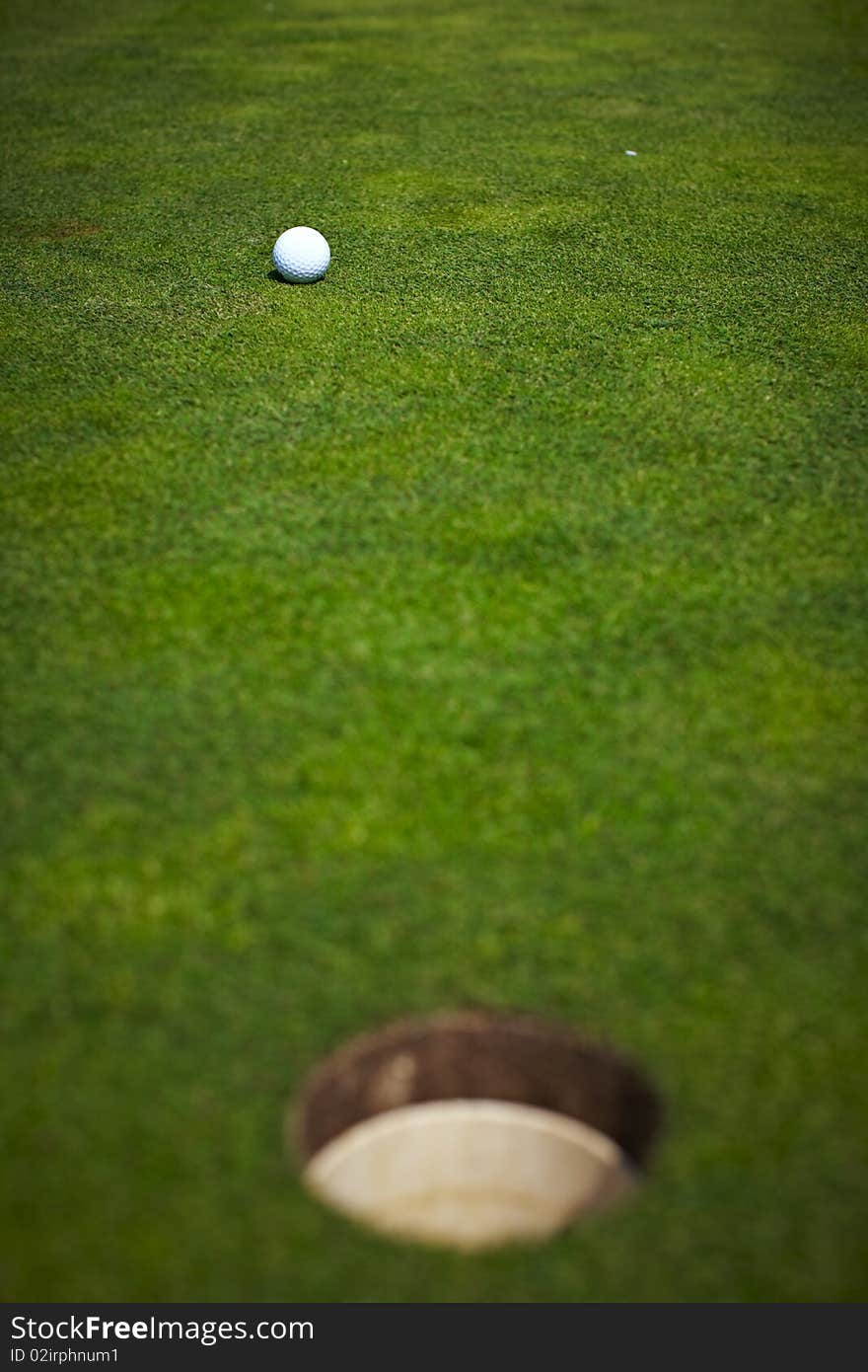 Single golf ball beside the hole