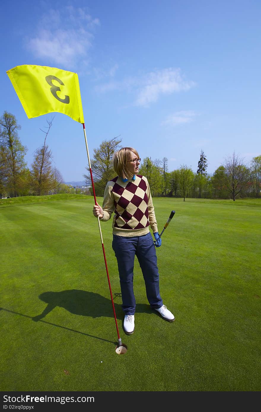 Woman holding a yellow flag number three on a golf course. Woman holding a yellow flag number three on a golf course.