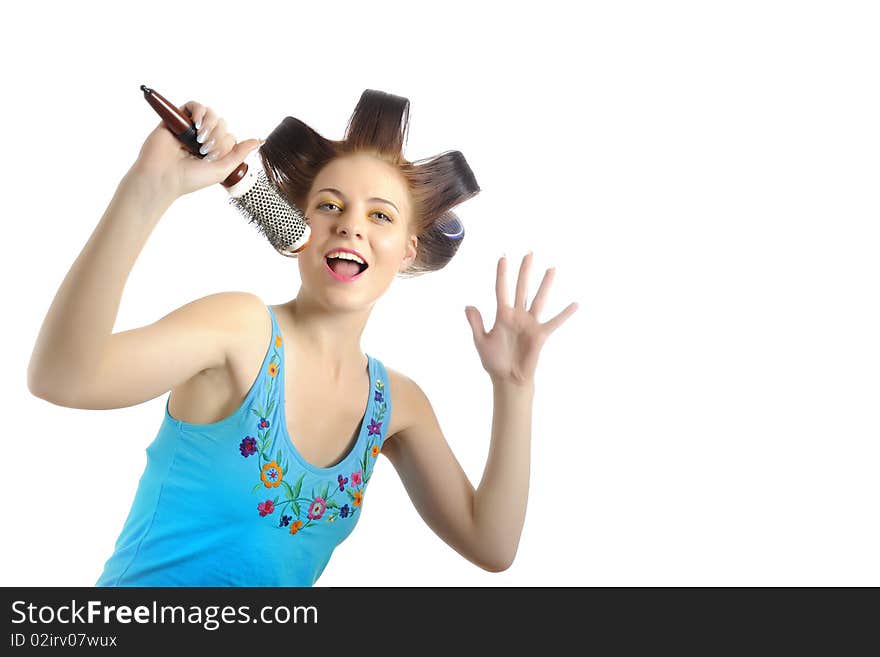 Young beautiful woman singing to the brush microphone while getting her hairstyle done with curlers on her hair. isolated on white background. copy-space. Young beautiful woman singing to the brush microphone while getting her hairstyle done with curlers on her hair. isolated on white background. copy-space