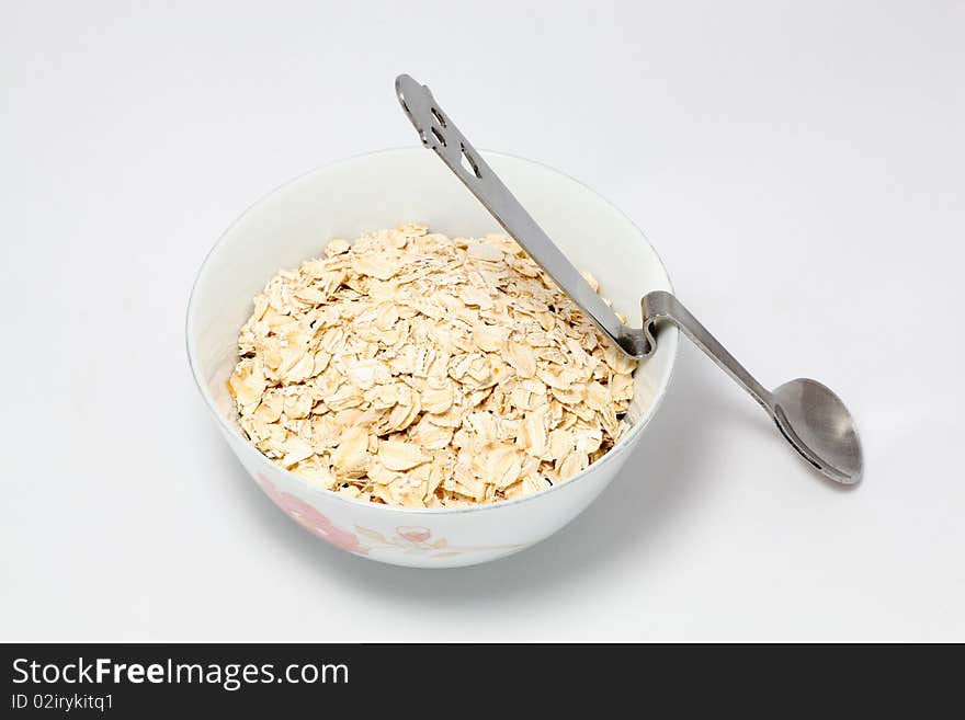 Bowl full of Oat and a spoon on white background. Bowl full of Oat and a spoon on white background