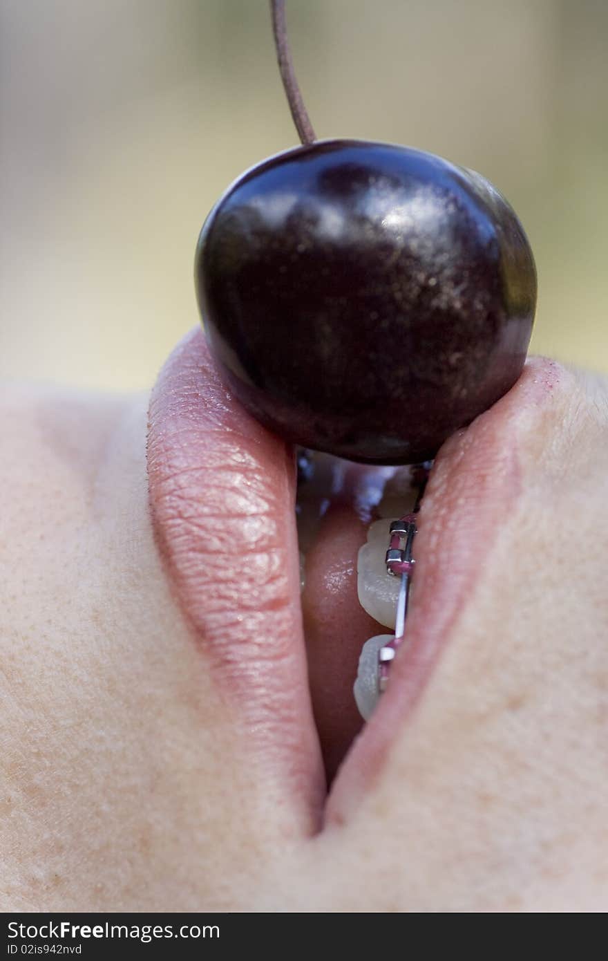 Close up view of a woman trying to eat a cherry. Close up view of a woman trying to eat a cherry.