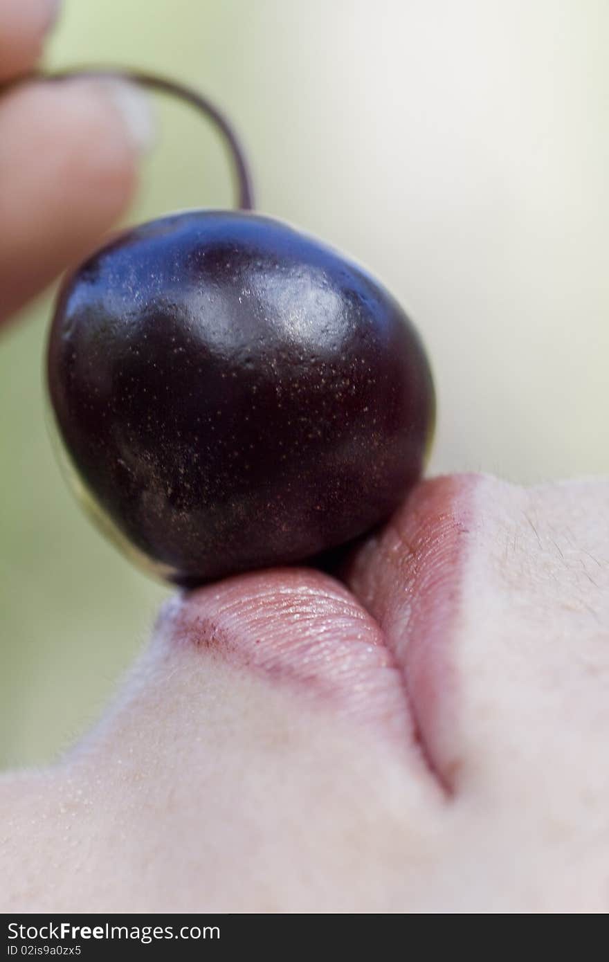 Close up view of a woman trying to eat a cherry. Close up view of a woman trying to eat a cherry.