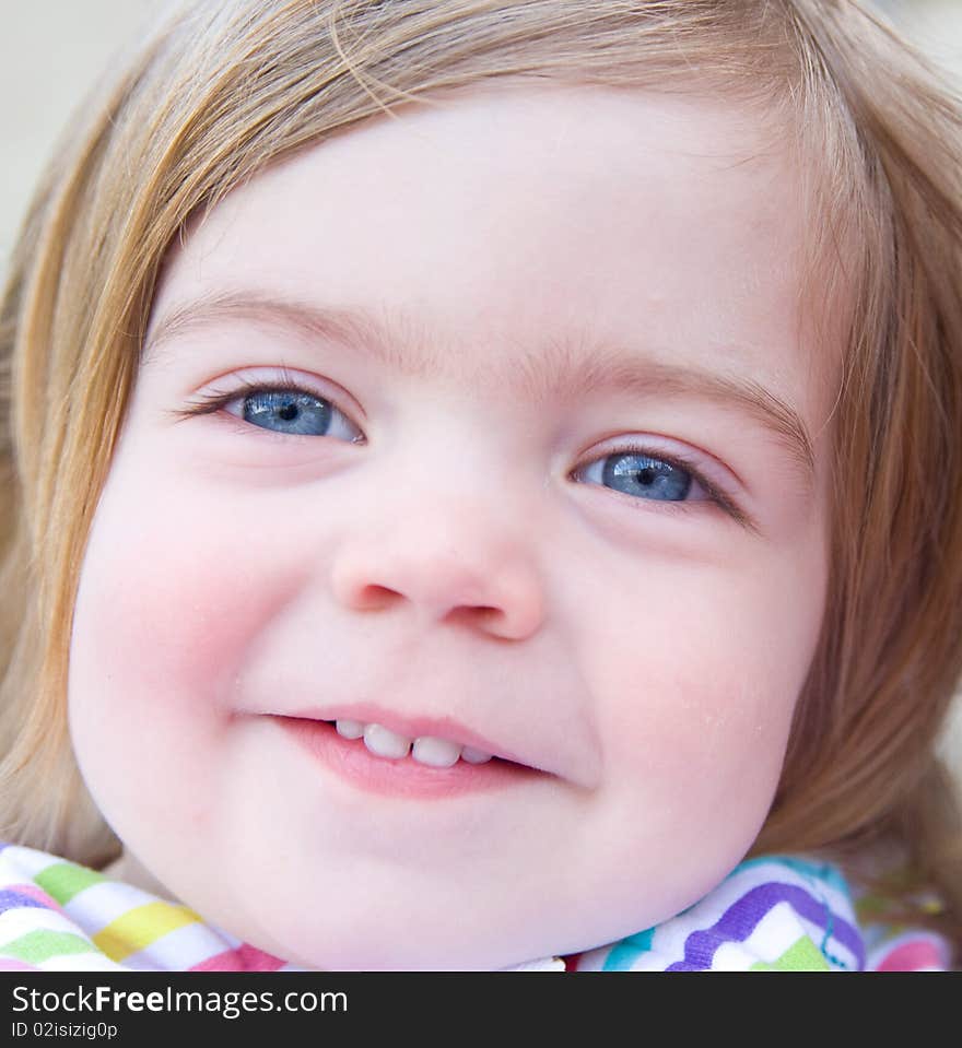 A close up portrait image of a blond blue eyed baby girl with a lovely smile. A close up portrait image of a blond blue eyed baby girl with a lovely smile.